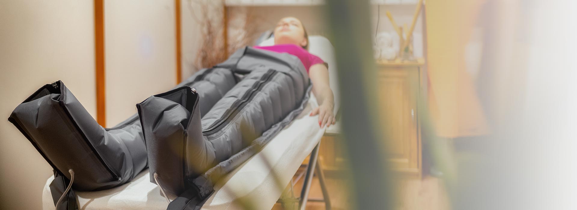 Eine Person liegt entspannt auf einem Tisch mit grauen Kompressionsstiefeln.