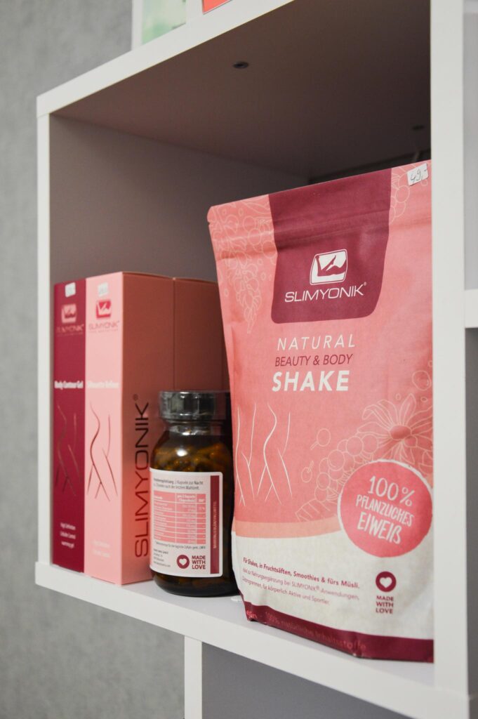 Regal im Innenraum mit rosa und roten Produktverpackungen und Flasche.
